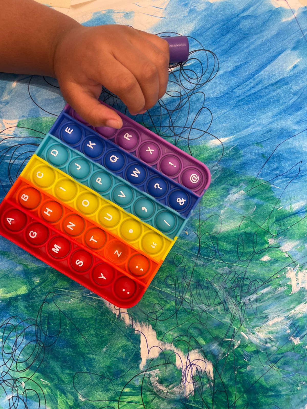Niño usando un pop-it de letras del alfabeto durante una sesión de terapia